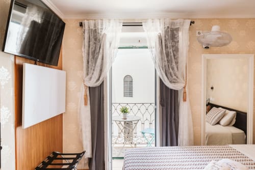 Charme da Graça hotel room in Lisboa with balcony, TV, and elegant curtains