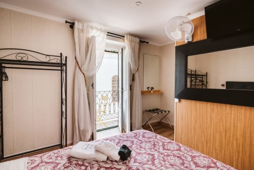 Charme da Graça hotel room in Lisboa with iron bed frame, balcony access, wooden furnishings, and fan