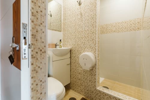 Modern bathroom with beige mosaic tiles, sink, toilet, and walk-in shower at Charme da Graça hotel in Lisboa