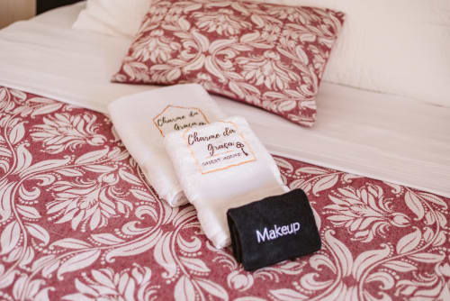 Charme da Graça hotel guest toiletries and makeup remover on bed with decorative burgundy pillows