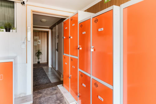 Modern hostel corridor at Charme da Graça Lisboa with bright orange lockers and white framing, shared guest facilities