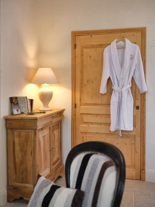 Chambre douillette à la Ferme Saint-Georges en Provence avec armoire en bois, peignoir blanc, lampe et chaise rayée