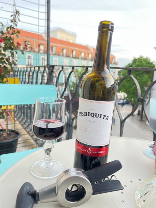 Periquita wine bottle and glass on balcony at Charme da Graça hotel, Lisboa with city views