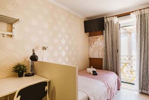 Single bedroom at Charme da Graça hotel in Lisbon with desk, TV, and balcony overlooking the city