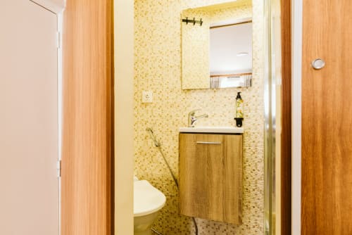 Modern bathroom with yellow mosaic tiles, wooden vanity, and mirror at Charme da Graça hotel in Lisbon