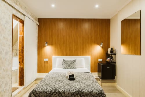 Modern hotel bedroom at Charme da Graça Lisboa with wooden accent wall, white bed, dark patterned bedding, and ensuite