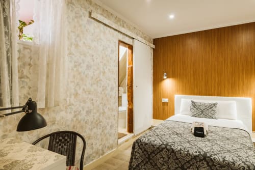 Modern hotel room at Charme da Graça in Lisboa with wooden accent wall, bed, desk, and en-suite bathroom