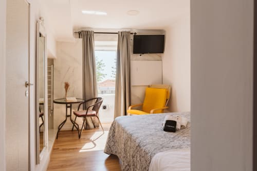 Modern double bedroom at Charme da Graça hotel in Lisbon with en-suite bathroom, TV, desk, and yellow accent chair