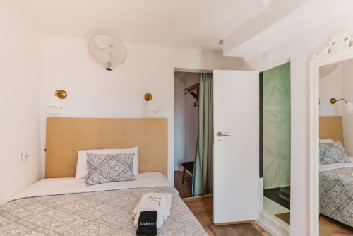 Charme da Graça hotel room in Lisbon with double bed, golden headboard, en-suite bathroom, and modern amenities