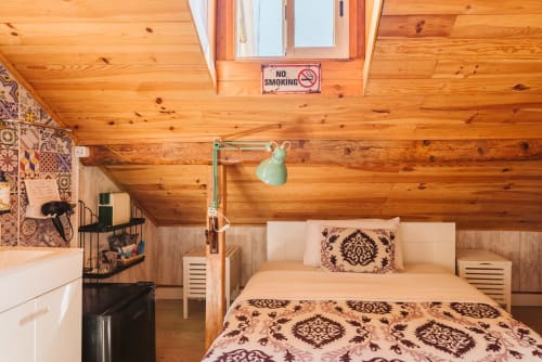 Cozy wooden cabin bedroom at Charme da Graça hotel in Lisbon with twin beds, patterned bedding, and rustic ceiling beams