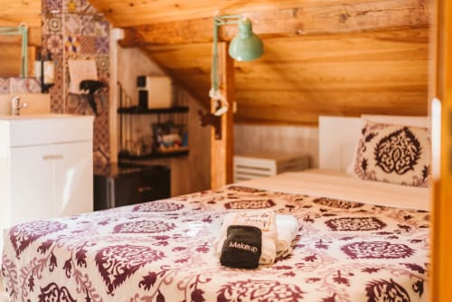 Charme da Graça luxury bedroom in Lisbon with wooden beams, decorative pillows, and green lamp fixture