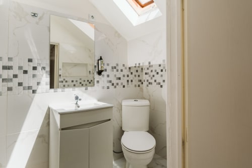 Modern bathroom in Charme da Graça hotel, Lisboa with marble tiles, vanity sink, toilet, and skylight