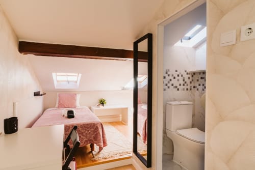 Charme da Graça lisbon attic room with pink bedding, skylight, and ensuite bathroom with black door frame