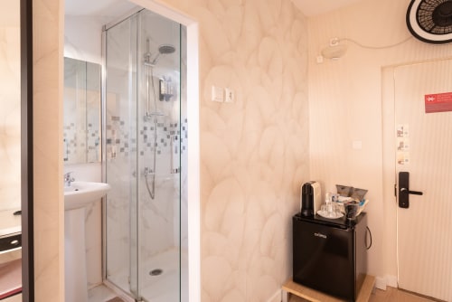 Modern bathroom at Charme da Graça hotel in Lisbon with glass shower enclosure, sink, and black electric kettle on wooden