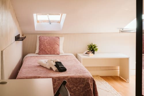 Charme da Graça hotel attic room in Lisboa with pink bedding, skylight, and modern furnishings