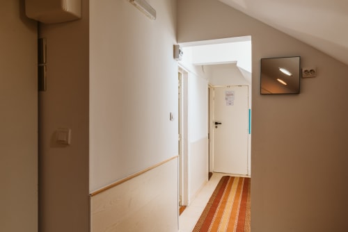 Hallway at Charme da Graça hotel in Lisboa with wooden doors, striped rug, and white walls