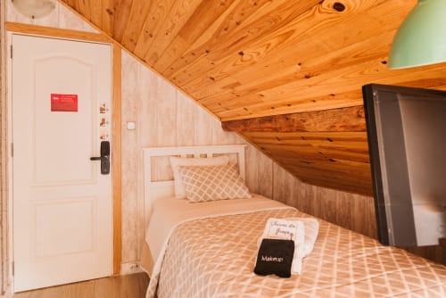 Single bedroom at Charme da Graça hotel in Lisbon with wooden ceiling, bed with patterned bedding, and TV