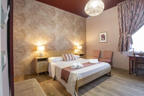 Stanza Corallo all'Epimoni B&B di Catania con letto matrimoniale, parete accent con stampa di palme, lampade comodino e vista sulla città