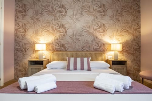 Camera Corallo Epimoni B&B a Catania con letto matrimoniale, testata in rattan e carta da parati con foglie tropicali