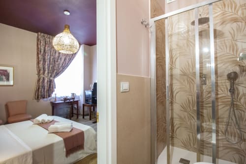 Camera Corallo presso Epimoni Catania con letto matrimoniale, soffitto viola, lampada a sospensione e bagno moderno con doccia in piastrelle decorate