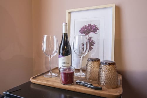 Bottiglia di vino, bicchieri e candele decorative su una mensola in legno nella suite Corallo di Epimoni, Catania