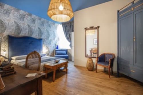 Elegante camera tripla presso l'Epimoni B&B a Catania con parete blu, arredamento in legno e servizi moderni