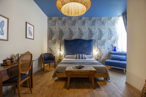 Camera tripla Oltremare presso l'Epimoni B&B Catania con testata blu, carta da parati decorativa, scrivania in legno e vista sulla città