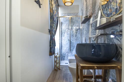 Bagno Oltremare dell'Epimoni B&B Catania con lavabo nero, carta da parati tropicale e finiture moderne