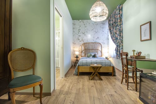Camera Alga dell'Epimoni B&B di Catania con pareti verdi, arredi in legno, lampada sospesa in vimini e camera da letto privata