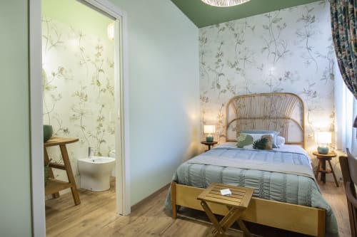 Camera Alga presso l'Epimoni B&B di Catania con letto a testata in rattan, carta da parati botanica e bagno en suite