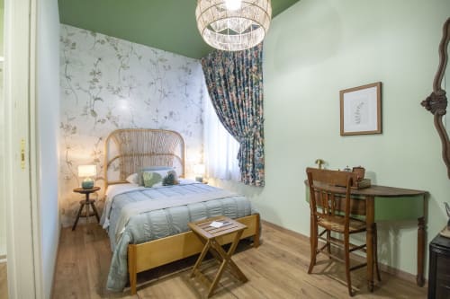 Accogliente camera singola presso Epimoni B&B a Catania con testiera in rattan, pareti verdi, scrivania e decori botanici