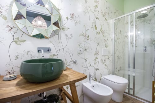 Moderno bagno dell'Epimoni B&B a Catania con lavabo in ceramica verde, carta da parati botanica, vanità in legno, bidet e WC
