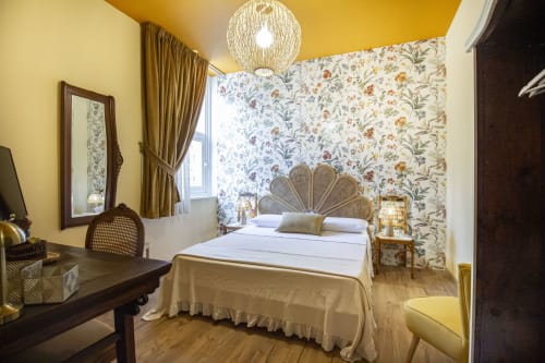 Camera Anemone presso Epimoni B&B Catania: letto matrimoniale con testata in vimini, carta da parati floreale, pareti gialle e vista città