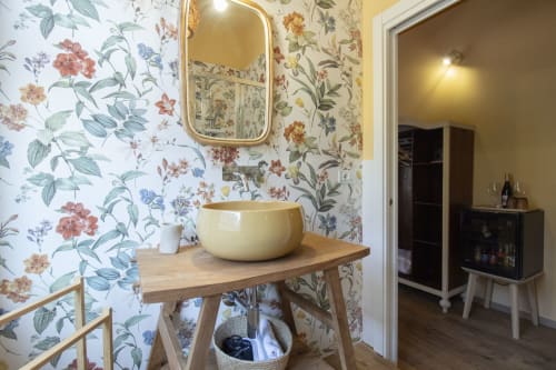 Bagno della camera Anemone presso l'Epimoni B&B Catania, con carta da parati floreale, lavabo a bacinella e mobile in legno.