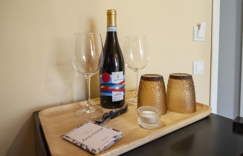 Bottiglia di vino, bicchieri e decorazioni dorate su tavolo di legno nella camera Anemone dell'Epimoni B&B, Catania