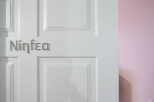 Ingresso della camera Ninfea presso l'Epimoni B&B di Catania, Italia con porta bianca moderna e parete con accento rosa