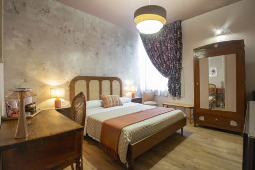 Spaziosa camera doppia presso Epimoni B&B Catania con letto in legno, testata in rattan, arredi eleganti e servizi moderni