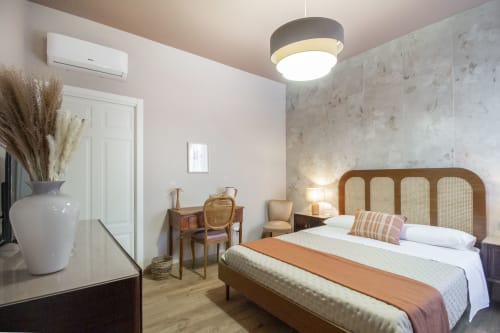 Camera Ninfea dell'Epimoni B&B a Catania con letto in legno, testiera in rattan e comfort moderni