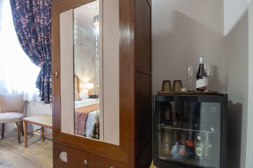 Stanza Ninfea presso Epimoni B&B Catania: armadio con specchio, mobile bar, sedia, tende blu, vista camera da letto
