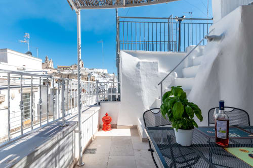 Terrazza soleggiata della boutique B&B Pietra & Luce a Ostuni, Italia con vista sul mare, basilico in vaso e architettura biancata