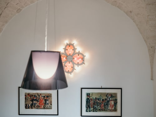 Muro bianco arcuato a Pietra & Luce Ostuni con lampada a sospensione e stampe d'arte moderna