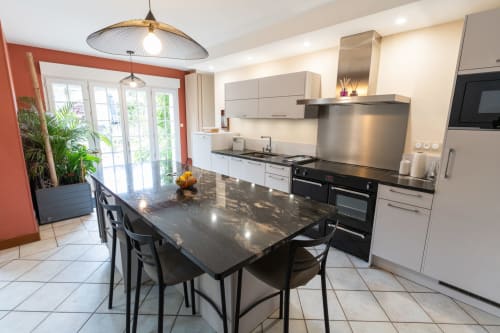 Cuisine moderne avec ilot central, piano de cuisson électrique 5 feux , 3 fours, réfrigérateur, micro-ondes et lave vaisselle.