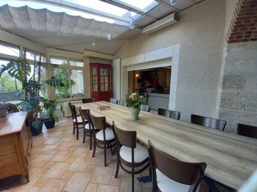 Véranda salle à manger avec grande table et chaises. 