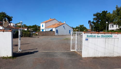 Entrée du Hameau des Chardons avec portail blanc et bâtisse au toit orangé, L'Aiguillon-la-Presqu'île