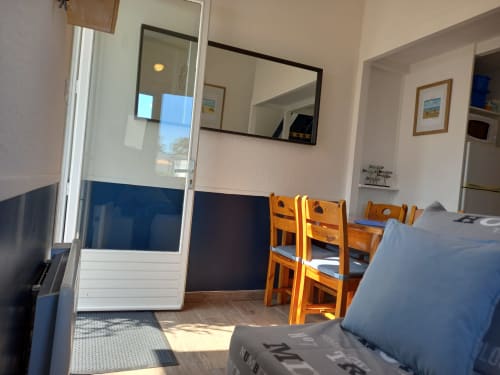 Appartement cosy aux Relais-Orbigny avec chaises de salle à manger en bois, téléviseur écran plat et vue sur le jardin à L'Aiguillon-la-Presqu'île