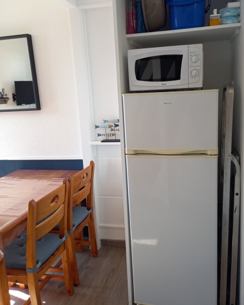 Cuisine de l'appartement Atlantique aux Relais-Orbigny avec réfrigérateur blanc, micro-ondes, table à manger en bois et