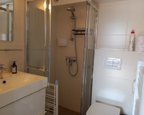 Salle de bain moderne aux Relais-Orbigny avec douche à l'italienne, lavabo blanc et murs carrelés à L'Aiguillon-la-Presqu'île, France
