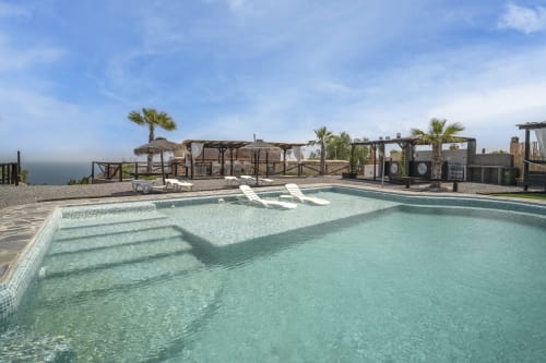 Piscina turquesa con área poco profunda en villa Paraje la Suerte en Adra, España, con vistas al mar, palmeras y tumbonas