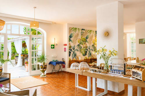 Area reception del Villa Bina Sea Hotel con decorazioni tropicali, pavimenti in legno e vista sul giardino a Serrara Fontana