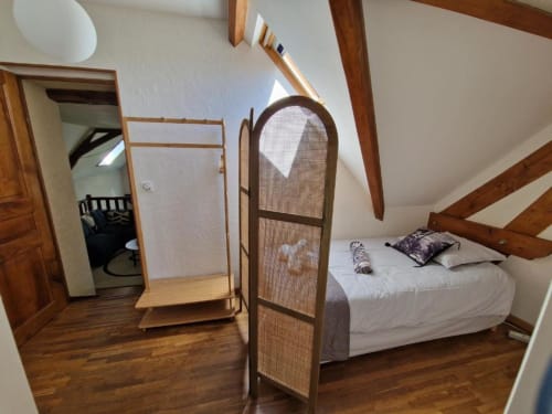 Coin nuit avec lit simple 90, paravent pour plus d'intimité et portant à vêtements.